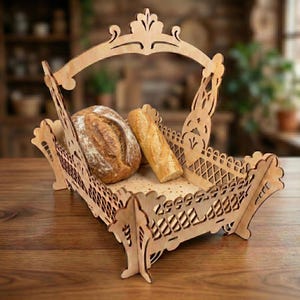 May include: A decorative wooden bread basket with a handle, holding a round loaf and a baguette. The basket has an intricate cut-out design and is made of light-colored wood. The bread is golden brown and appears freshly baked.