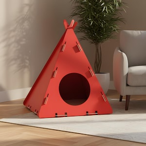 Puede incluir: Una casa para mascotas roja, triangular, con forma de tipi. La estructura tiene una entrada circular y est&aacute; construida con paneles entrelazados. La casa para mascotas est&aacute; sobre una alfombra clara, con una planta y un sill&oacute;n gris en el fondo.