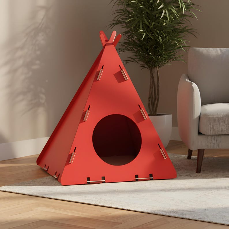 Puede incluir: Una casa para mascotas roja, triangular, con forma de tipi. La estructura tiene una entrada circular y est&aacute; construida con paneles entrelazados. La casa para mascotas est&aacute; sobre una alfombra clara, con una planta y un sill&oacute;n gris en el fondo.