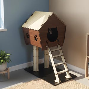 Puede incluir: Una casa para gatos de madera con cuerpo marr&oacute;n, techo beige y base negra. La casa presenta una silueta de gato y huellas de patas. Una peque&ntilde;a escalera proporciona acceso a la casa elevada. Un accesorio para mascotas acogedor y elegante.