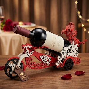 May include: A red and white decorative wine bottle holder shaped like a motorcycle. The holder has intricate cut-out designs and holds a bottle of red wine. A small leather tag reads "LIMITED EDITION".