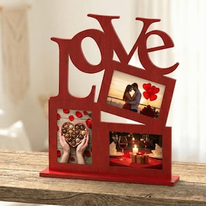 May include: A red wooden photo frame in the shape of the word "LOVE". The frame holds three photos: a couple, a box of chocolates, and a romantic dinner setting. The frame sits on a wooden surface.