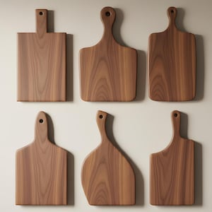 Puede incluir: Seis tablas de cortar de madera con asas se muestran sobre un fondo neutro. Las tablas varían en forma, con diseños rectangulares y curvos. La veta de la madera es visible, mostrando un tono cálido y natural. Estas tablas son ideales para la cocina.
