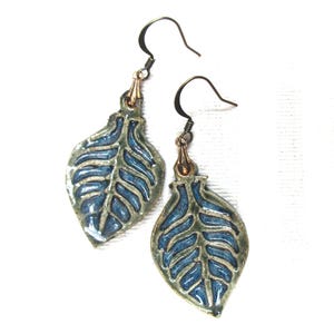 May include: A pair of blue and green ceramic leaf earrings with a gold-toned hook.