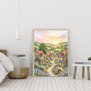 Op de afbeelding: Een ingelijste muurkunstprint met een landelijk dorpsgezicht met stenen huisjes, een kronkelend stenen pad en levendige bloementuinen onder een zachte pastelkleurige zonsonderganghemel met glooiende groene heuvels op de achtergrond.