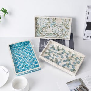 May include: Three rectangular trays with inlaid shell patterns. One tray features a bright blue fish scale design, another displays a muted green and white leaf motif, and the third shows a soft blue and white scalloped pattern on a white base.