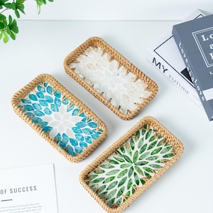 May include: Three rectangular woven trays with decorative floral patterns in blue, white, and green. The trays have a natural woven border and are arranged on a white surface. The trays are ideal for serving or displaying small items.
