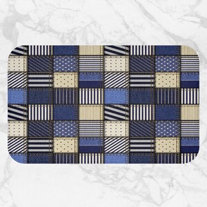 May include: Rectangular bath mat with a patchwork design. The mat features squares of various blue denim fabrics, beige, and white fabrics with striped and dotted patterns. The edges are rounded.