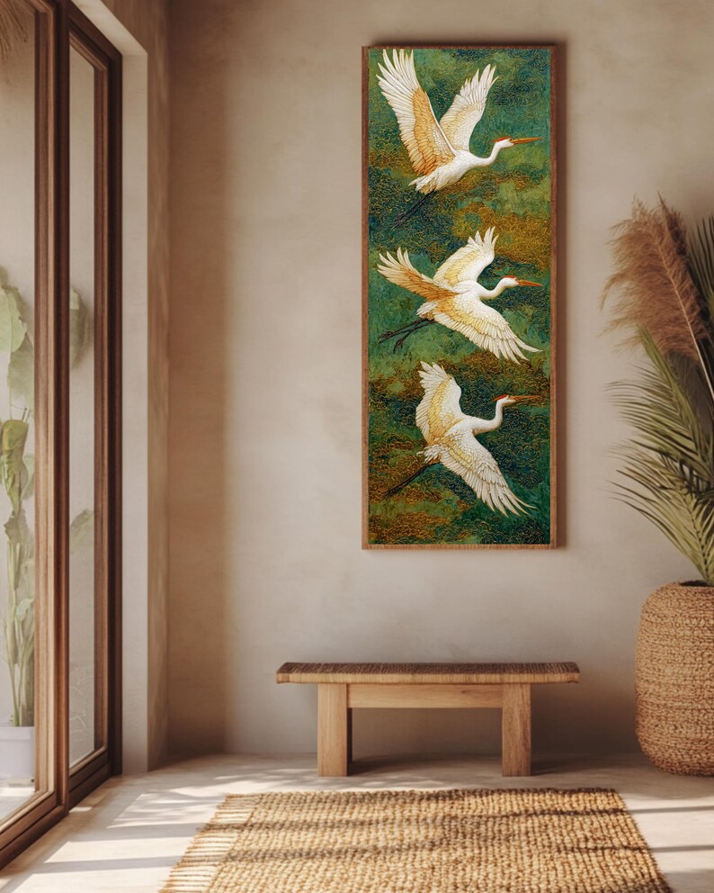 May include: A vertical framed artwork features three white birds with outstretched wings against a green and gold background. The birds have orange beaks and accents. The artwork hangs on a neutral-colored wall, above a wooden bench and a woven rug.