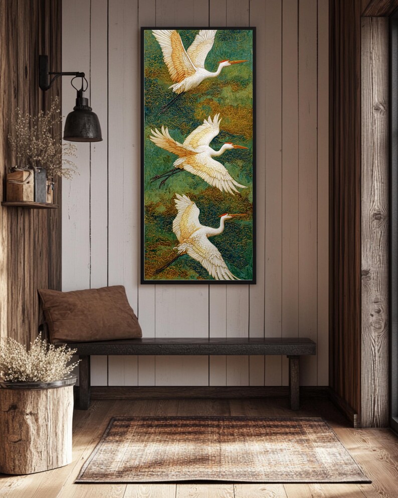 May include: A vertical framed artwork features three white birds with orange beaks and wingtips in flight against a green and gold background. The artwork hangs above a dark wooden bench in a rustic interior setting.
