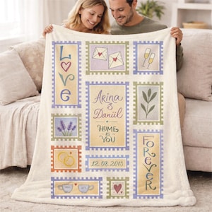 May include: A cream-coloured blanket with a collage of postage stamp-style designs. The stamps include the words "LOVE" and "FOREVER", wedding rings, hearts, and the names "Arina & Daniil" with the date "12.08.2013".