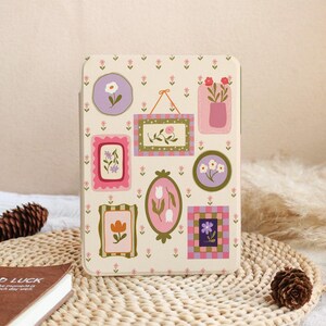Peut inclure: Une coque de tablette rectangulaire sur fond crème arborant un motif répétitif de petites fleurs roses et diverses illustrations encadrées de sujets botaniques, incluant des tulipes, des marguerites et d'autres compositions florales.