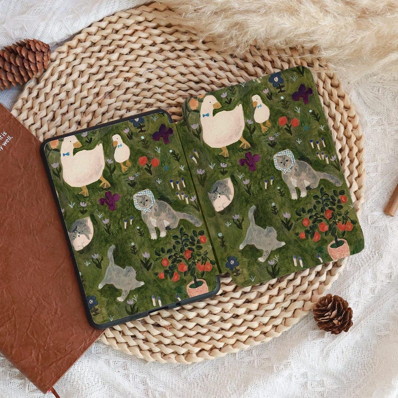 May include: Two open tablet cases with a whimsical design featuring ducks, cats, and flowers on a green background. The cases are decorated with illustrations of ducks wearing bow ties, cats wearing bonnets, and potted plants.