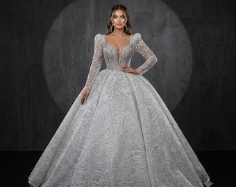 Abito da sposa con pizzo, perline e cristalli, maniche lunghe, scollo a cuore e strascico, su misura.
