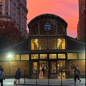 May include: A vibrant sunset over a city street with a subway entrance. The sky transitions from pink to purple. A building with a sign that reads "72" is in the center. People are walking on the crosswalk.