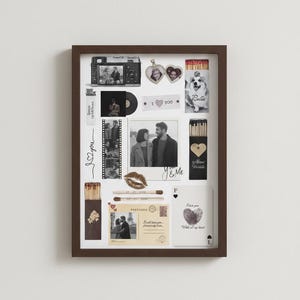 May include: A framed collage featuring romantic memorabilia. Includes photos, a film strip, matches, a postcard, and playing cards. The collage has a dark brown frame and is arranged on a white background. The theme is love and relationships.