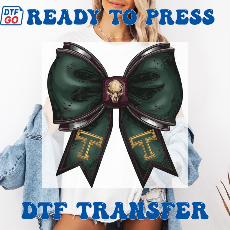 Puede incluir: Un dise&ntilde;o de lazo verde y burdeos con una pieza central de calavera y detalles dorados con la letra "T". Las palabras "READY TO PRESS" y "DTF TRANSFER" est&aacute;n impresas en azul.