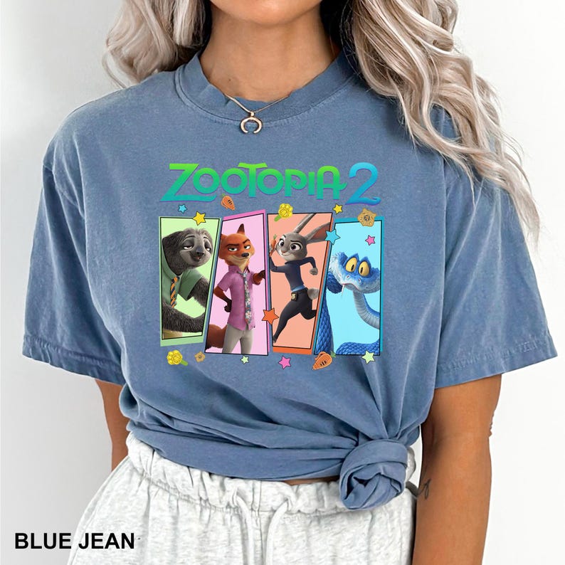 May include: Blue jean colored t-shirt featuring the text "ZOOTOPIA 2" in green and orange. The shirt has a graphic of four characters from the movie Zootopia. The bottom of the shirt has the text "BLUE JEAN".