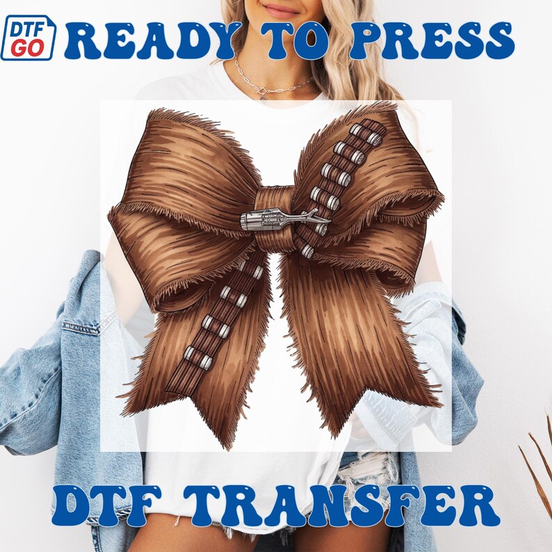 Puede incluir: Un dise&ntilde;o de lazo marr&oacute;n con textura peluda, que recuerda a la piel de un personaje de una pel&iacute;cula de ciencia ficci&oacute;n. El lazo presenta un detalle plateado y marr&oacute;n en forma de cintur&oacute;n en el centro. El texto "READY TO PRESS" y "DTF TRANSFER" est&aacute; en azul.