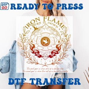 May include: White t-shirt featuring a circular design with the text "IRON FLAME BURN IT DOWN". The design includes a central emblem with a bird, surrounded by flames and botanical elements in shades of gold and red. The shirt also has the text "READY TO PRESS" and "DTF TRANSFER".