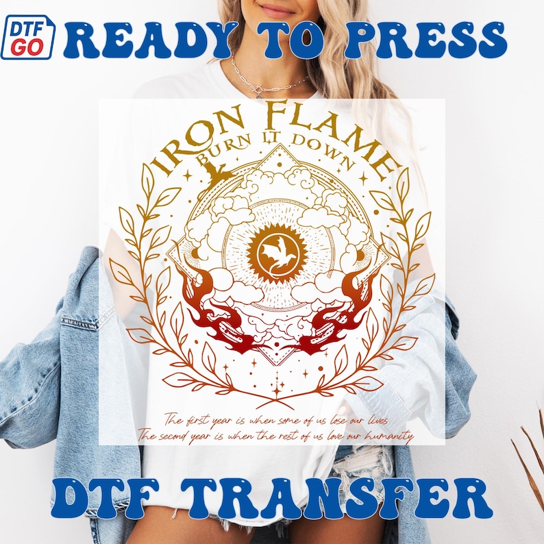 May include: White t-shirt featuring a circular design with the text "IRON FLAME BURN IT DOWN". The design includes a central emblem with a bird, surrounded by flames and botanical elements in shades of gold and red. The shirt also has the text "READY TO PRESS" and "DTF TRANSFER".