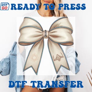 Puede incluir: Dise&ntilde;o de lazo color crema con ribete azul claro y cierre met&aacute;lico. El lazo presenta un sol y una ilustraci&oacute;n de nave espacial en las colas. Las palabras "READY TO PRESS" y "DTF TRANSFER" est&aacute;n impresas en azul.
