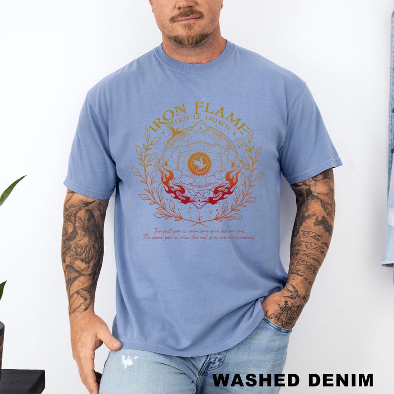 May include: A light blue t-shirt with a circular graphic featuring the text "IRON FLAME TURN IT DOWN" in orange and gold. The graphic includes flames and floral elements. The words "WASHED DENIM" are printed at the bottom.