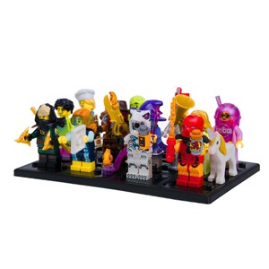May include: A collection of colorful Lego minifigures on a black base. The figures include a ninja, a chef, a robot, and others, each with unique accessories and designs. The figures are arranged closely together.