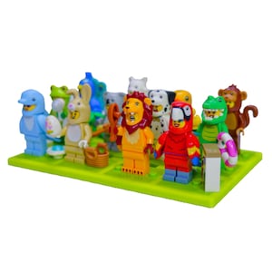 May include: A collection of colorful toy figures, each designed as a different animal. The figures include a blue dolphin, a green frog, a rabbit, a lion, a parrot, a crocodile, and a monkey. They are arranged on a green base.