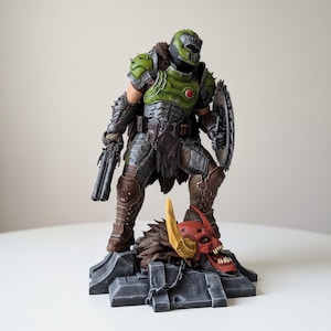 May include: A detailed figurine of a character in green and silver armor, holding a double-barreled gun and a shield. The figure stands on a stone base with a demon skull. The figure is approximately 12 inches tall.