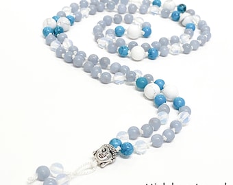 May include: A blue, white, and turquoise beaded mala necklace with a silver Buddha charm. The necklace is made with semi-precious stones and is approximately 108 beads long.