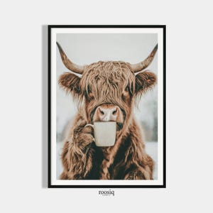 Può includere: Stampa incorniciata raffigurante una mucca delle Highlands che tiene in mano una tazza bianca. La mucca ha lunghi peli marroni e ispidi, grandi corna e si trova su uno sfondo sfocato. La stampa ha un'estetica minimalista e la parola "roosiq" è stampata in basso.