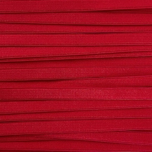 May include: Close-up of several strips of red elastic ribbon, arranged horizontally. The ribbon has a subtle sheen and a slightly textured surface. The color is a vibrant, solid red, and the arrangement creates a layered effect.