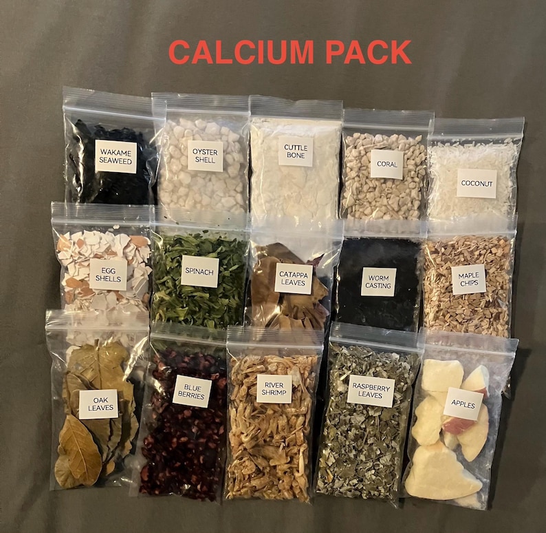 May include: A collection of small, clear plastic bags filled with various natural ingredients, including seaweed, oyster shell, and spinach. The bags are labeled with the contents, and the text "CALCIUM PACK" is displayed at the top. The contents are for aquarium use.