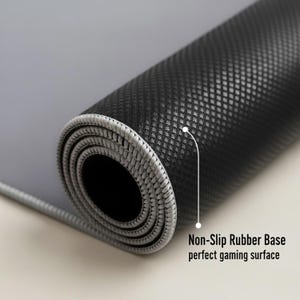 May include: Rolled-up gray and black gaming mouse pad. The mouse pad has a non-slip rubber base and a textured surface. The edge is stitched with gray thread. Text on the image reads: Non-Slip Rubber Base perfect gaming surface.
