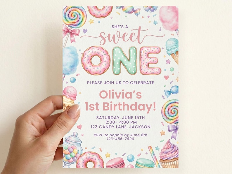 May include: A rectangular birthday invitation card featuring colorful watercolor illustrations of donuts, lollipops, cupcakes, and candy. The text reads: SHE'S A sweet ONE, PLEASE JOIN US TO CELEBRATE, Olivia's 1st Birthday!, SATURDAY, JUNE 15TH, 2:00- 4:00 PM, 123 CANDY LANE, JACKSON, RSVP to Sophie by June 6th, 123-456-7890.