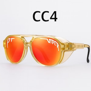 Puede incluir: Gafas de sol transparentes estilo aviador con lentes naranjas. Las gafas tienen una montura dorada y el texto "VIPER" est&aacute; impreso en la lente. El texto "CC4" est&aacute; impreso encima de las gafas.