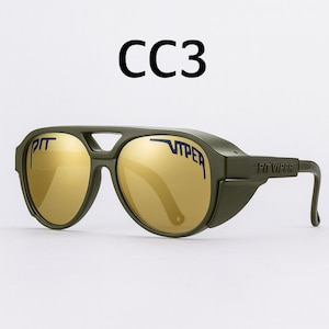 Puede incluir: Gafas de sol Pit Viper verde oliva con lentes doradas. El texto "CC3" est&aacute; encima de las gafas de sol. El nombre de la marca "PIT VIPER" est&aacute; impreso en las lentes y las patillas.
