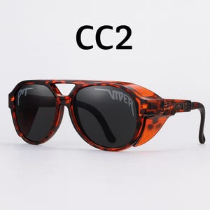 Puede incluir: Gafas de sol con estampado de carey y lentes oscuras. Las gafas de sol tienen un dise&ntilde;o distintivo de aviador con protectores laterales y el texto "CC2" encima de la montura. Las lentes est&aacute;n marcadas con la palabra "VIPER".