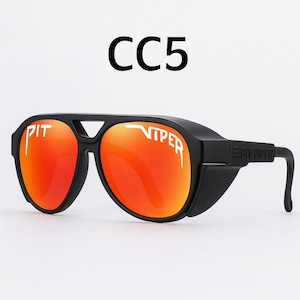 Puede incluir: Gafas de sol negras con lentes naranjas. Las gafas de sol tienen el texto "PIT VIPER" en blanco en las lentes y "CC5" encima de la montura. Las patillas de las gafas tienen el texto "PIT VIPER" en blanco.