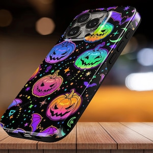 May include: A black smartphone case featuring a vibrant, multi-coloured pattern of jack-o'-lanterns, purple bats, and small stars. The pumpkins are rendered in gradients of neon pink, orange, green, and blue against a dark background.