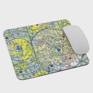 May include: A rectangular mousepad featuring a detailed aviation sectional chart of the Washington, D.C. area, with a white mouse resting on the right side. The chart is in shades of yellow, blue, and green, with numerous lines, symbols, and text.