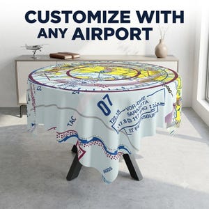 May include: A round tablecloth featuring a detailed aviation sectional chart print with navigational data, including VOR-DME Sarasota, frequency 122.1R, and the text 'CUSTOMIZE WITH ANY AIRPORT' displayed prominently above the table in dark blue letters.