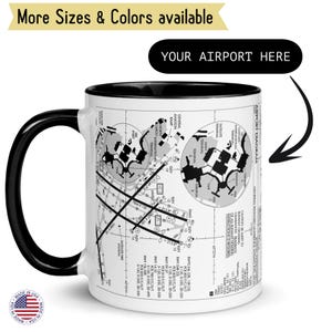 Pode incluir: Uma caneca de cerâmica branca com alça e borda pretas, com um design de diagrama de aeroporto. A caneca tem o texto "YOUR AIRPORT HERE" e "More Sizes & Colors available". Um pequeno adesivo "Made in USA" é visível.