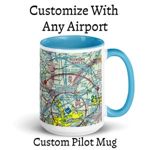 May include: A white ceramic mug with a light blue interior and handle, featuring a detailed aviation sectional chart print. The text "Customize With Any Airport" appears above the mug, and "Custom Pilot Mug" appears below the mug.