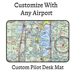 Peut inclure: Un tapis de bureau rectangulaire présentant une carte aéronautique détaillée de la région d'Oshkosh, Wisconsin. Le texte 'Customize With Any Airport' et 'Custom Pilot Desk Mat' figure au-dessus et au-dessous de la carte affichant des données.
