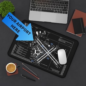 May include: Black mousepad with a detailed airport diagram in white and blue. A white mouse sits on the pad, with a laptop and notepad in the background. The text "YOUR AIRPORT HERE" is on a blue arrow.