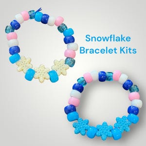 Könnte beinhalten: Zwei Armbänder mit Perlen mit dem Text "Snowflake Bracelet Kits". Die Armbänder weisen eine Vielzahl farbenfroher Perlen in Rosa-, Blau-, Weiß- und Klartönen mit schneeförmigen Akzenten auf.