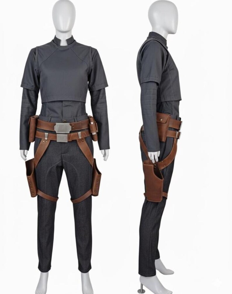 May include: A dark gray short-sleeved top and matching trousers worn with a brown leather utility belt featuring metallic buckles and two attached holsters. The ensemble includes a structured bodice overlay and fitted pants with a clean finish.