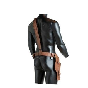 May include: A brown leather holster system featuring a waist belt and a single shoulder strap. The belt includes a side-mounted holster pouch and two small cylindrical loops for holding items. The leather has a smooth, matte finish throughout.